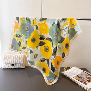 Détail du foulard en soie aux motifs floraux montrant la texture douce et brillante