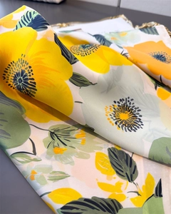 Gros plan d'un foulard en soie à imprimé floral avec fleurs jaunes sur fond rose clair