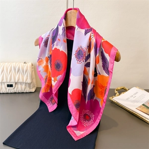 Foulard en soie synthétique aux motifs floraux vifs rose et orange sur un cintre chic