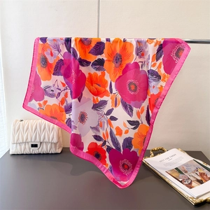 Détail d'un foulard en soie aux motifs floraux élégants et bordures rose vif