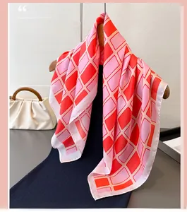 Close-up of geometric plaid print silk scarf in pink and red with glossy texture