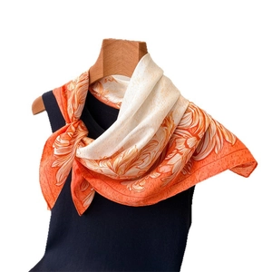 Floral print silk square scarf in orange and cream white on a display stand