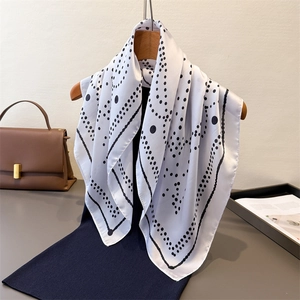 Polka dot silk-feel square scarf with wave patterns hanging on a wooden hanger