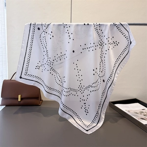 Detail of silk-like square scarf featuring black geometric polka dot patterns on white fabric