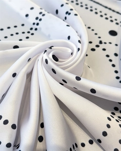 Close-up of silky satin fabric with geometric black polka dots in a spiral drape