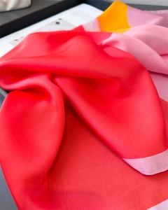 Detail eines roten Seidentuchs mit rosa-orangefarbenem Color-Blocking auf Tablett