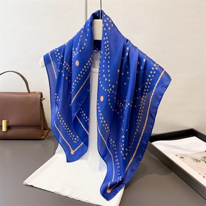 Fashionable geometric silk scarf in royal blue and orange pattern draped over white vest