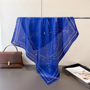 Close-up of geometric polka dot patterns on blue silk scarf with fine rolled edges