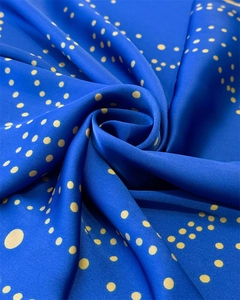 Detail of blue silk scarf with golden polka dot pattern showing smooth texture and drapes