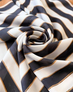 Detailed view of striped faux silk scarf with elegant black, white, and gold patterns
