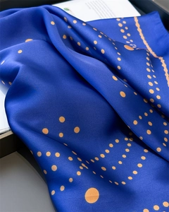 Close-up of royal blue silk scarf featuring geometric polka dots and fine edge stitching