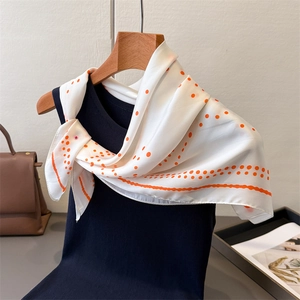 Detailed view of silk-like square scarf with orange polka dots and elegant wavy border