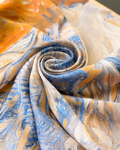 Détail d'un foulard en soie montrant une texture de peinture à l'huile orange et bleue