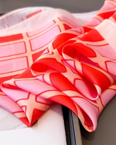 Close-up of geometric plaid pattern on red and pink silk satin scarf with soft texture