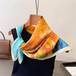 Détail d'un foulard en soie à imprimé tournesols sur un cintre en bois avec maille