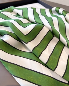 Detail shot of green and white chevron patterned silk scarf with premium satin texture