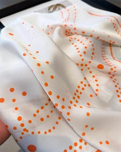 Detail of silk-like white scarf with orange polka dots showing soft folds and texture