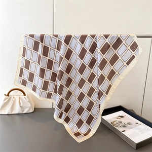 Detail showing the geometric brown and blue silk scarf draped elegantly on a metal rack