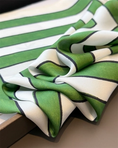 Close-up of green and white striped silk scarf showing soft satin texture and black borders