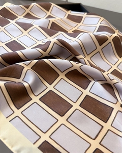 Detailed view of geometric brown and grey checkered silk scarf with satin finish texture