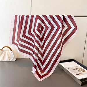 Detail of silk-like square scarf featuring geometric diamond patterns and fine hem edges