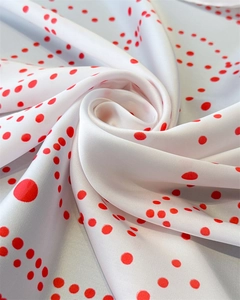 Detailed view of white silk-like satin fabric with elegant red polka dot pattern print