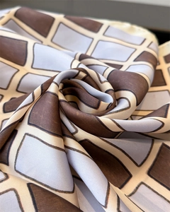 Macro shot of geometric checkered silk scarf showing glossy texture and drape detail