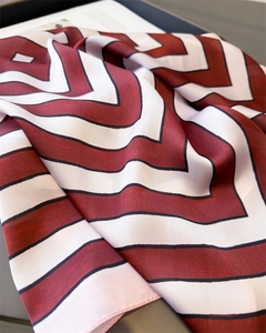 Detail shot of the geometric V-stripe pattern and smooth texture of the silk-like scarf