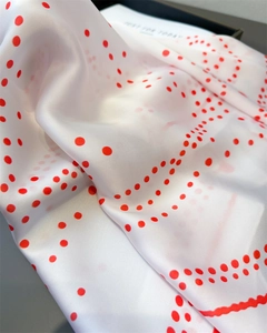 Macro shot of polished white silk scarf with red polka dots showing premium texture