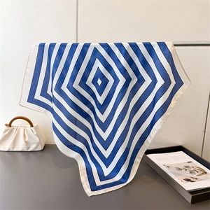 Detail of silk-like scarf with blue and white geometric patterns draped on a metal rack