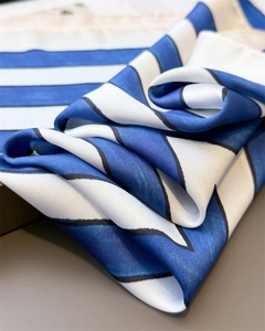 Close-up of geometric striped silk scarf showing satin texture and blue-white pattern