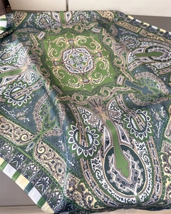 Close-up of green paisley silk scarf with detailed vintage patterns and hemmed edges