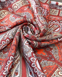 Detailed close-up of folded silk scarf with classic paisley patterns and silky texture