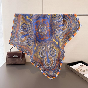 Close-up of bohemian paisley silk scarf with vibrant blue and orange floral patterns