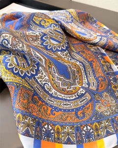 Detailed close-up of paisley pattern silk scarf with vibrant blue and orange hues