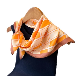 Orange and cream geometric silk-like scarf tied on a hanger for a stylish look