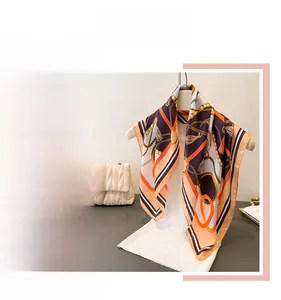 Detail of silk-like scarf featuring classic chain and tassel print in orange and black