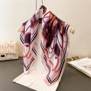 Close-up of silk scarf with elegant chain and tassel pattern draped on a model stand