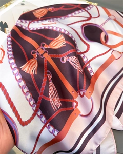 Detailed close-up of silk-like scarf featuring classic chain and tassel print patterns