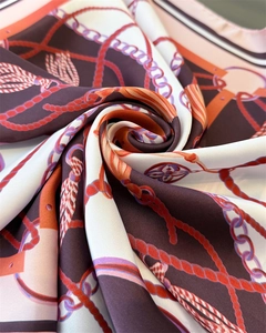 Macro shot of silk scarf detailing elegant chain and tassel prints in brown and orange