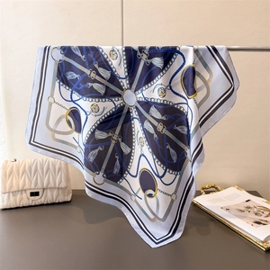Close-up of square silk scarf with classic chain and tassel patterns in navy blue and gold