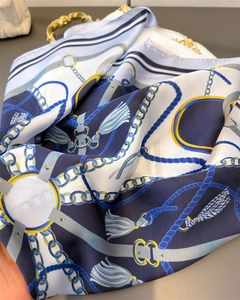 Detail of blue and white silk-like scarf with chain and tassel patterns on a gold tray