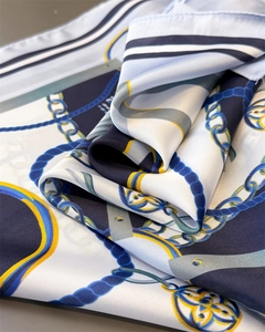 Macro detail of nautical chain print silk scarf with luxury blue and yellow motifs