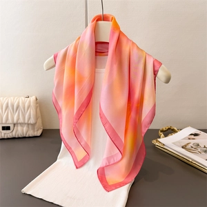 Elegant gradient silk scarf featuring soft pink to orange sunset tones and rolled edges