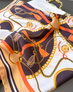 Detailed view of silk-like scarf with chains, tassels, and elegant satin texture