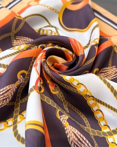Detailed macro shot of luxury silk scarf showing chain patterns and smooth fabric texture
