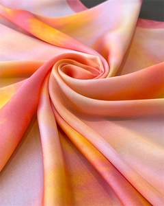 Close-up of silk scarf showing vibrant pink and orange gradient with elegant satin luster