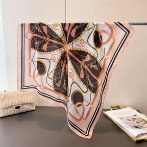 Close-up of silk-like scarf featuring elegant chain patterns and tassel prints on smooth fabric