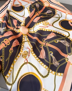 Detailed close-up of a satin silk scarf featuring gold chain and pink tassel patterns