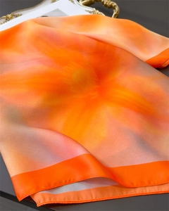 Detailed macro view of orange floral silk scarf with glossy satin texture and elegant drape